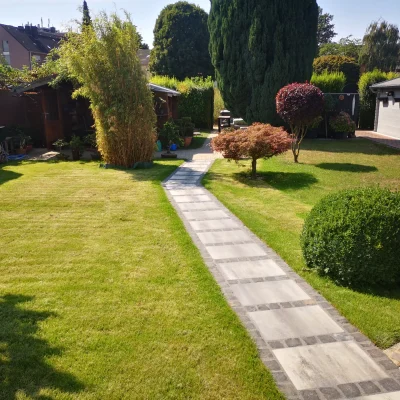 Abgeschlossene Gartenanlage mit Rasenflächen, Büschen und Gehwegen nach der Fertigstellung durch Markus Lillot.
